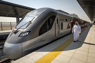 A man walks past an Etihad Rail train at Dubai's Yalayis station on September 29, 2026, during the inaugural passenger service connecting from Abu Dhabi's Mohamed Bin Zayed City station to Dubai.