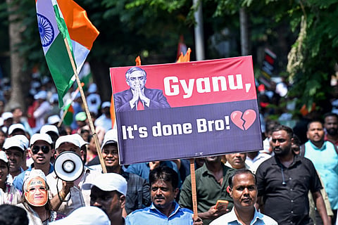 A protester carries a placard next to India's national flag during a demonstration calling for the resignation the country's Chief Election Commissioner Gyanesh Kumar over alleged irregularities in the Special Intensive Revision (SIR) of electoral rolls, in Mumbai on October 4, 2026.