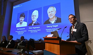 Nobel Committee Secretary General Thomas Perlmann ) speaks to the media in front of a screen displaying the names of this year's laureates (from left) Karl Deisseroth, Peter Hegemann and Georg Nagel during the announcement of the winners of the 2026 Nobel Prize in Physiology or Medicine at the Karolinska Institute in Stockholm, Sweden, on October 5, 2026.