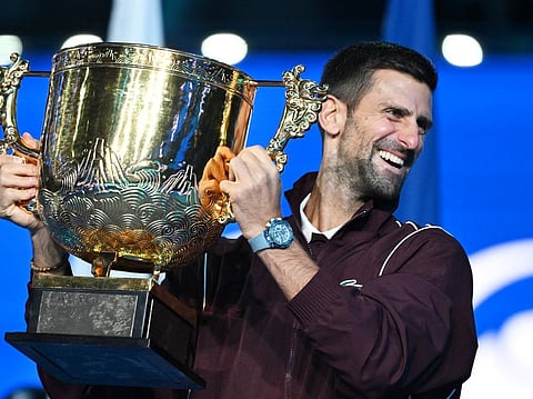 Serbia’s Novak Djokovic holds up the trophy as he celebrates winning the men’s singles final against Australia’s Alex de Minaur at the China Open tennis tournament in Beijing on October 6, 2026.