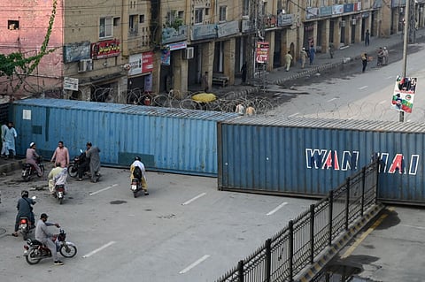Commuters gather at a road blocked with shipping containers amid ongoing protests by the opposition Pakistan Tehreek-e-Insaf (PTI) party demanding the release of jailed former prime minister Imran Khan in Peshawar on October 11, 2026. 