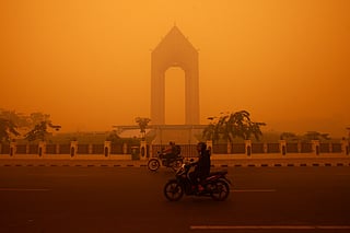Motorcyclists ride in the morning in Palangkaraya, Central Kalimantan on October 14, 2026, amid thick haze from forest and land fires in the region.