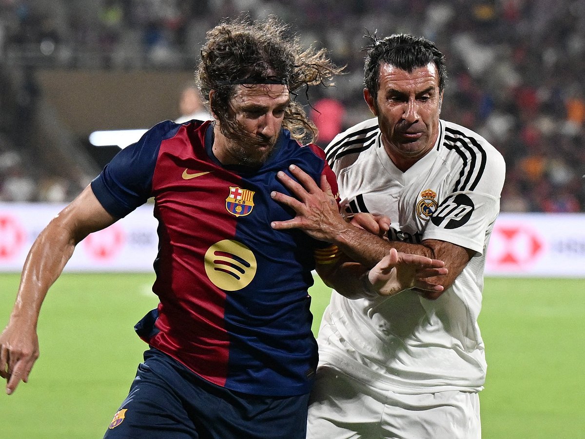 Real Madrid's Portuguese midfielder Luis Figo (R) and Barcelona's Spanish defender Carles Puyol struggle for the ball during Legends El Clasico football match between Real Madrid and Barcelona at the DY Patil Stadium in Navi Mumbai on April 6, 2025.