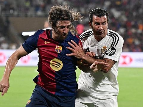 Real Madrid's Portuguese midfielder Luis Figo (R) and Barcelona's Spanish defender Carles Puyol struggle for the ball during Legends El Clasico football match between Real Madrid and Barcelona at the DY Patil Stadium in Navi Mumbai on April 6, 2025.