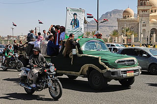 People ride in a pickup truck during a funeral procession for a Houthi officer in Sanaa, Yemen.