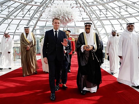 French President Emmanuel Macron (L) gestures as the Emir of Kuwait Sheikh Mishal Al Ahmad Al Jaber Al Sabah welcomes him upon arrival at Kuwait International Airport, in Kuwait City on October 19, 2026.