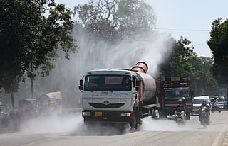A truck-mounted water sprinkler sprays tiny droplets of water to mitigate the effects of air pollution on a road near India Gate, in New Delhi on Monday.  