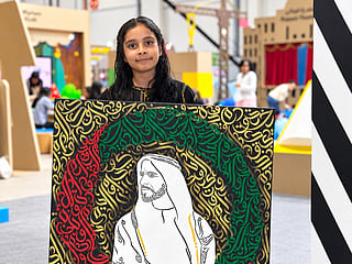 Nazmin holding her calligraphy portrait of Sheikh Zayed at the Abu Dhabi International Book Fair, created live in front of visitors.
