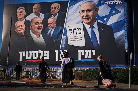 FILE - People walk past a Likud party campaign billboard featuring Israeli Prime Minister Benjamin Netanyahu alongside opposition party leaders and bearing the Hebrew slogan "Right or Palestine," ahead of Israel's general election, in Beni Brak, Israel, Sunday, Oct. 18, 2026.