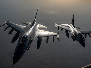 F-16 fighter jets approach a KC-135 Stratotanker to refuel while flying over the Middle East.