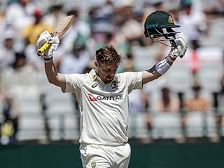 Australia's Josh Inglis raises his bat and helmet to celebrate after scoring a century on day three of the third Test match against South Africa at Newlands stadium in Cape Town on October 29, 2026.