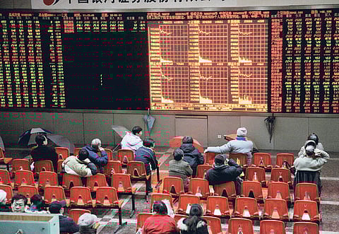 Investors watch the stock trading board at a securities exchange house in Shanghai.