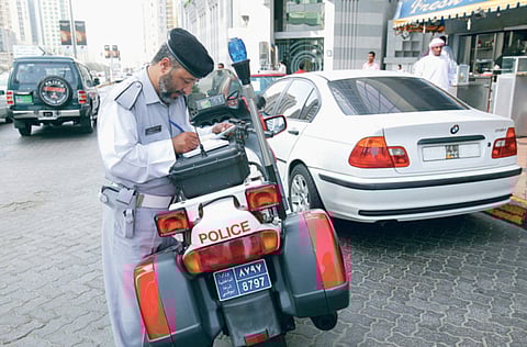 An Abu Dhabi traffic police officer writes up fines for traffic violators in Abu Dhabi. Police urged motorists to drive safely in order to avoid traffic violations.