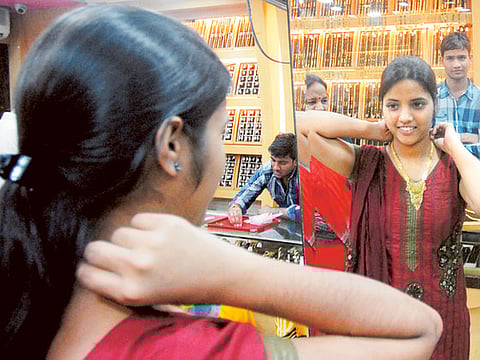 A woman tries a gold pendant at a jewellery shop in Mumbai,India. Picture for illustration purposes only. 