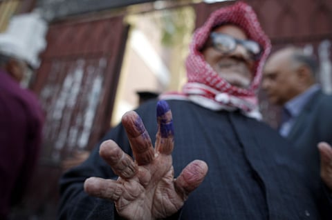 A man shows his ink-stained finger as he leaves a polling centre in Egypt.