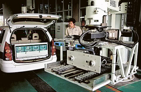 Workers watch as a battery exchange robot changes the batteries in an electric car at China’s largest electric vehicle battery recharging station in Beijing yesterday. China plans to allocate an annual fund of up to $315.06 million from this year to help develop and mass produce energy-saving vehicles to cut carbon emissions, the government said. 