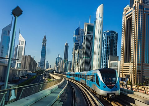 A Dubai Metro train runs past rows of high-rise buildings on Shaikh Zayed Road.