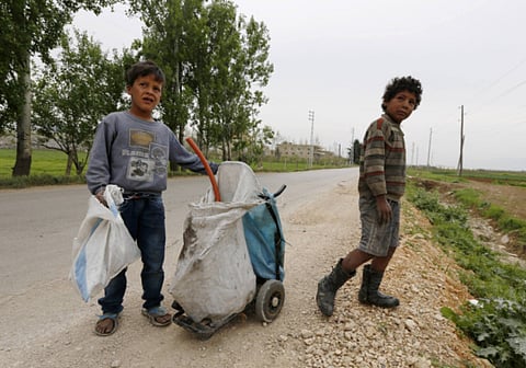 A Syrian refugee boy holds a bag as the other stands beside him in Bekaa valley, Lebanon. 