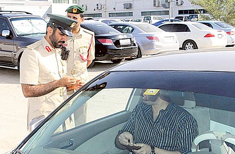 Picture for illustrative purpose: Dubai police official issues a fine to a motorist