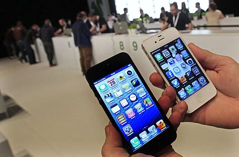 A customer holds up an Apple iPhone 5 (L) and iPhone 4S. Photo for illustrative purposes