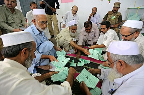 Polling staff counts ballots at a polling station during the by-election, in Peshawar, Sindh province of Pakistan in a file photo.