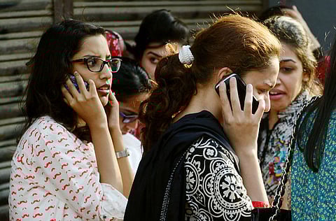 Pakistani office workers speak on their mobile phones. Pakistan raised $279 million in a sale of telecom spectrum at the base price.