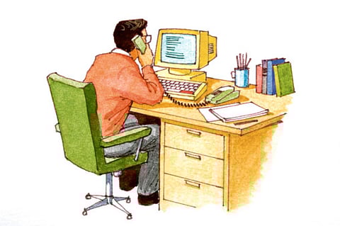 Man seated at desk talking on telephone