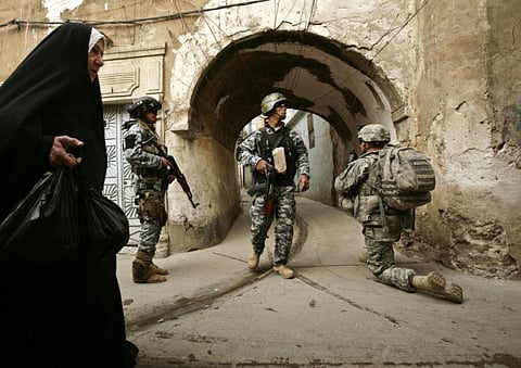 Illustrative image only: In this file photo, an Iraqi woman passes US troops and Iraqi police officers as they stand guard in the Bab Al Jadeed area of Mosul, 360 kilometers northwest of Baghdad, Iraq.