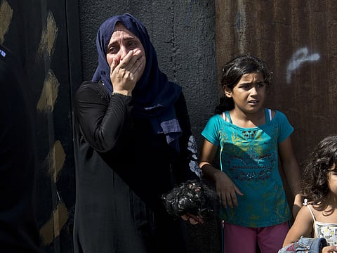 A Palestinian woman cries as she and other members of her family ran out of their house in a hurry in Gaza City