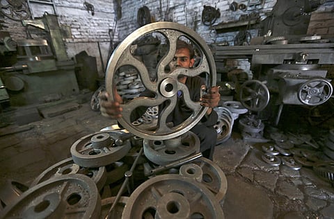 A worker checks the dimension of a wheel used in textile machinery inside a factory in the western Indian city of Ahmedabad. 
