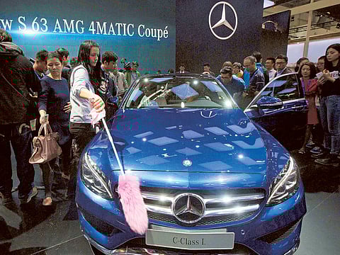 A staff member cleans a Mercedes car during the Auto China show in Beijing. Vehicle sales in China are set to fall about 8% this year.