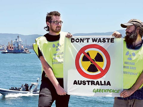Greenpeace activists hold a placard as a ship (top L) transporting reprocessed nuclear waste arrives at Port Kembla in New South Wales, April 2019.