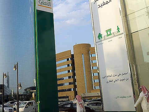 Saudi men walk in front of a branch of the 'National Commercial  Bank' (NCB) in the capital Riyadh. 