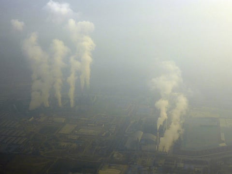 An aerial view shows smoke billowing from chimneys of factories located near Beijing, amid heavy smog under a red alert for air pollution, China, December 19, 2015. 