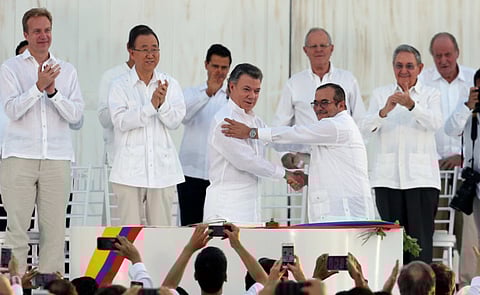 Colombia’s President Juan Manuel Santos, front left, and the top commander of the Revolutionary Armed Forces of Colombia (FARC) Rodrigo Londono, known by the alias Timochenko, shake hands after signing the peace agreement between Colombia’s government and the FARC to end over 50 years of conflict in Cartagena, Colombia, Monday, Sept. 26, 2016. Behind, from left, are Norway’s Foreign Minister Borge Brende, U.N. Secretary General Ban Ki Moon, Mexico's President Enrique Pena Nieto, Peru's President Pedro Pablo Kuczynski, Cuba's President Raul Castro, and Spain's former King Juan Carlos. (AP Photo/Fernando Vergara)