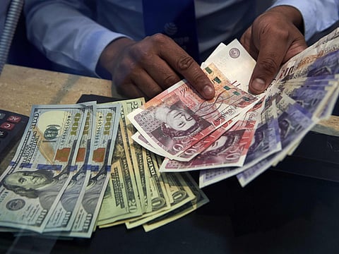 A cashier displays multiple denomination US dollar and British pound Sterling bank notes for a photograph inside a currency exchange store in central London.
