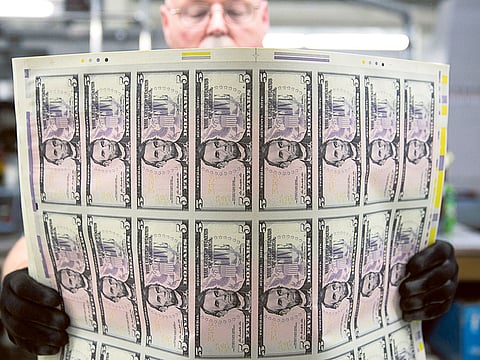 An employee uses a vibrating table to loosen stacks of five dollar notes before being cut into singles at the Bureau of Engraving and Printing in Washington, DC, US on Tuesday, April 23, 2013. 