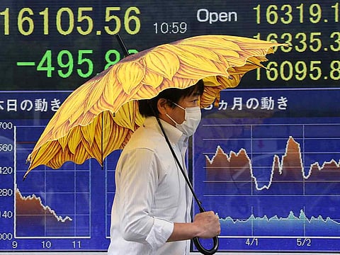 A man under a colorful umbrella walks by an electronic stock board of a securities firm in Tokyo showing Japan's benchmark Nikkei 225.  MSCI's broadest index of Asia-Pacific shares outside Japan was up 1.5% and eyeing its best session in a month. Japan's Nikkei rose 0.9% during Thursday's opening.