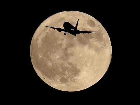 An airliner is silhouetted against a full moon Sunday, Oct. 20, 2002.