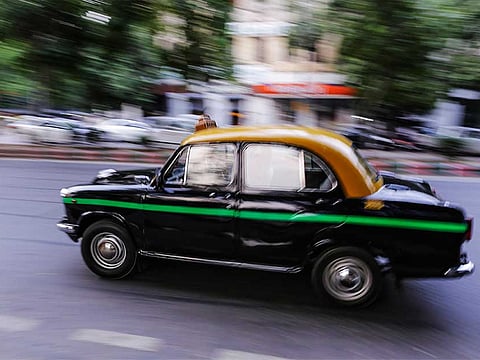 A Hindustan Motors Ltd. Ambassador taxi drives along a road in New Delhi. [Illustrative image only]