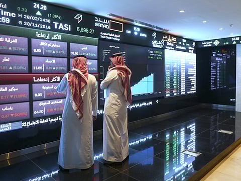 File picture used for illustrative purposes only. Visitors stand and watch stock movements displayed on large video screens inside the Saudi Stock Exchange.