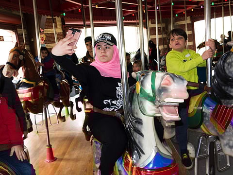 A group of mostly Syrian but some Iraqi refugee families take selfies in Times Square during a tour of Manhattan on April 21, 2017 in New York.