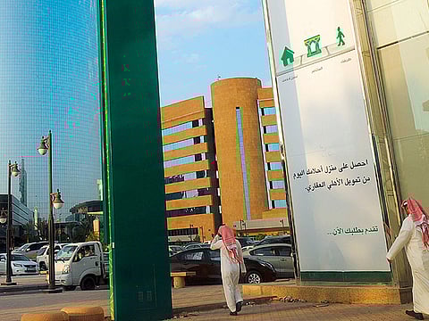 Saudi men walk in front of a branch of the ‘National Commercial  Bank’ (NCB) in the capital Riyadh. 