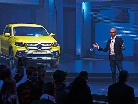 Volker Mornhinweg, head of Daimler AG Mercedes-Benz van division, speaks next to a Mercedes-Benz AG X-Class pickup truck during a launch event in Cape Town.  Daimler AG plans to slash headcount at its Mercedes-Benz cars division to help manage the disruptive shift to self-driving, electric cars.