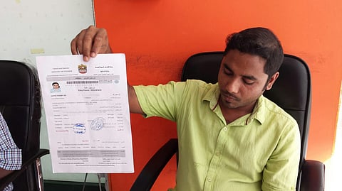 Abdul Rasheed, sales person at Abrar Al Madeena Studio in Abu Dhabi, holds an entry permit which he printed at his office. Photo for illustrative purposes.