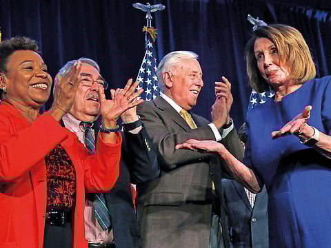 House Minority Leader Nancy Pelosi of California (right) dances after speaking about Democratic wins in the House of Representatives to a crowd of supporters in Washington, DC.