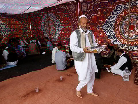 A man wears traditional clothes as he serves a traditional meal during a wedding in Junzur
