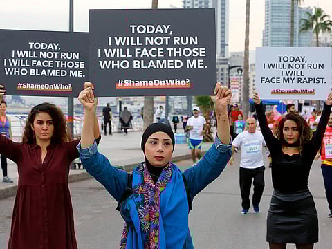 Protesters hold banners with messages against sexual assault during the 16th edition of the Beirut Marathon 