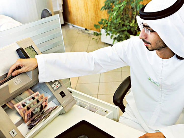 A teller counts dirham notes