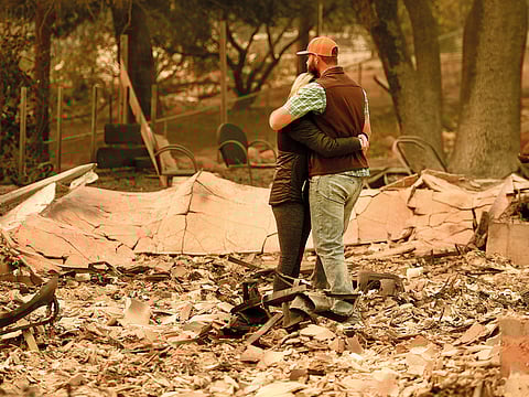 Chris and Nancy Brown embrace while looking over the remains of their burnt residence after the Camp Fire tore through the region in Paradise, California.